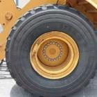 Close-up of a Caterpillar 950K wheel loader front tyre and wheel hub, with bucket linkage visible beside it