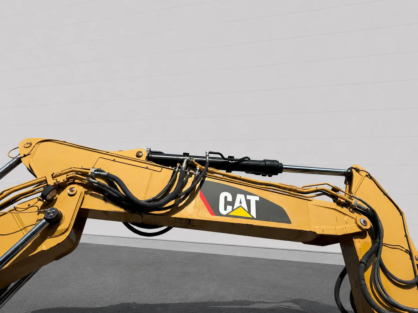 Close-up of Caterpillar 320 EL excavator boom, hydraulic cylinders and hoses with CAT logo